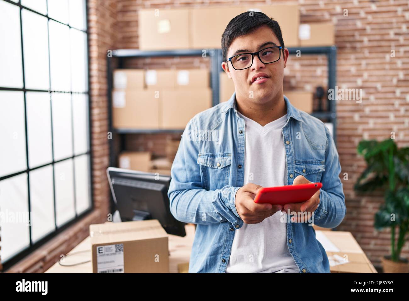 Down syndrome man ecommerce business worker using touchpad at office Stock Photo
