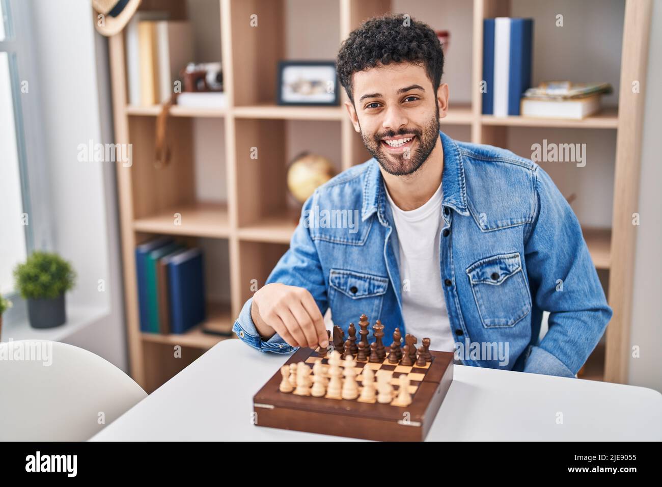 Young arab man playing chess sitting on table at home Stock Photo