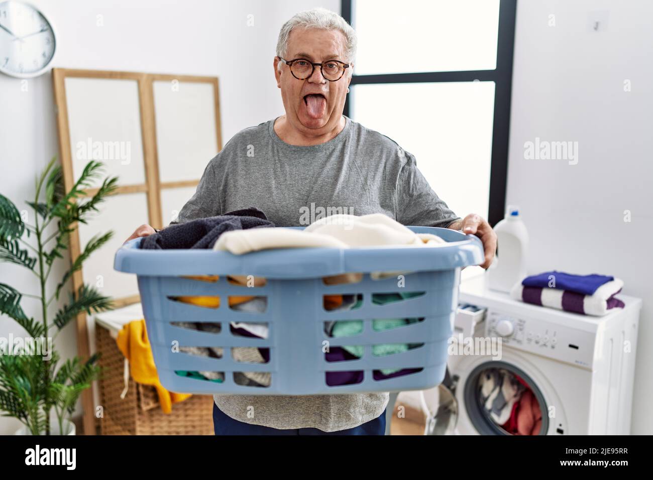Senior caucasian man holding detergent bottle at laundry room sticking