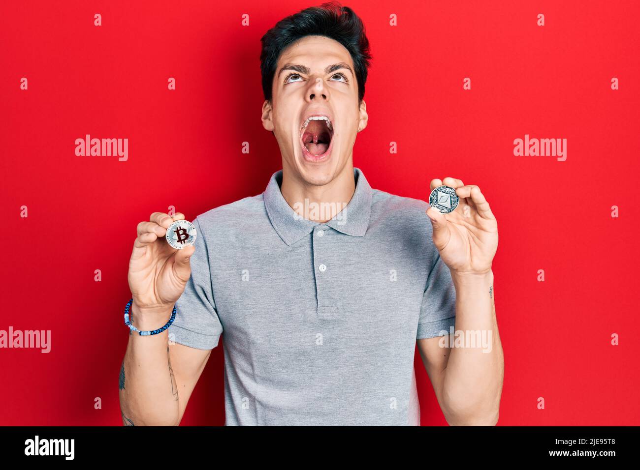 Young hispanic man holding virtual currency ethereum coin and bitcoin angry  and mad screaming frustrated and furious, shouting with anger looking up  Stock Photo - Alamy
