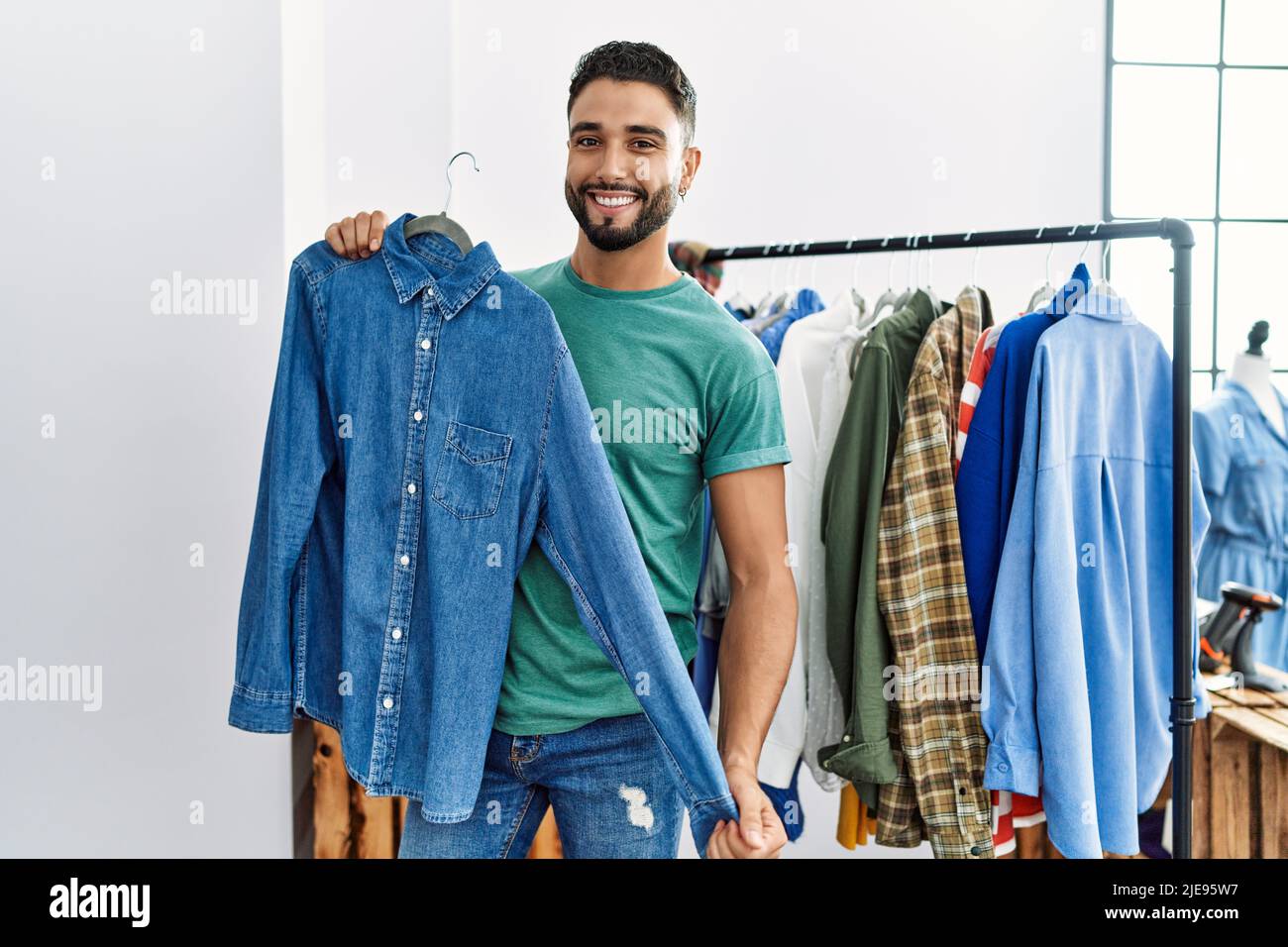 Young arab man customer smiling confident shopping at clothing store ...