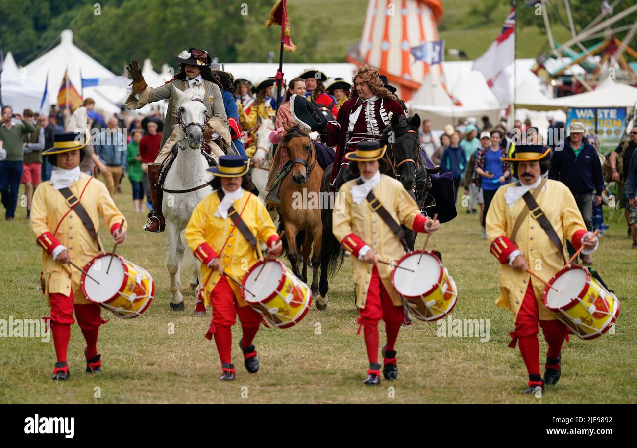 A person playing the role of King Charles II, (left on horseback) waves to the crown during a Restoration-era Pageant during the Chalke Valley History festival at Broad Chalke, Near Salisbury, Wiltshire. Picture date: Sunday June 26, 2022. Stock Photo