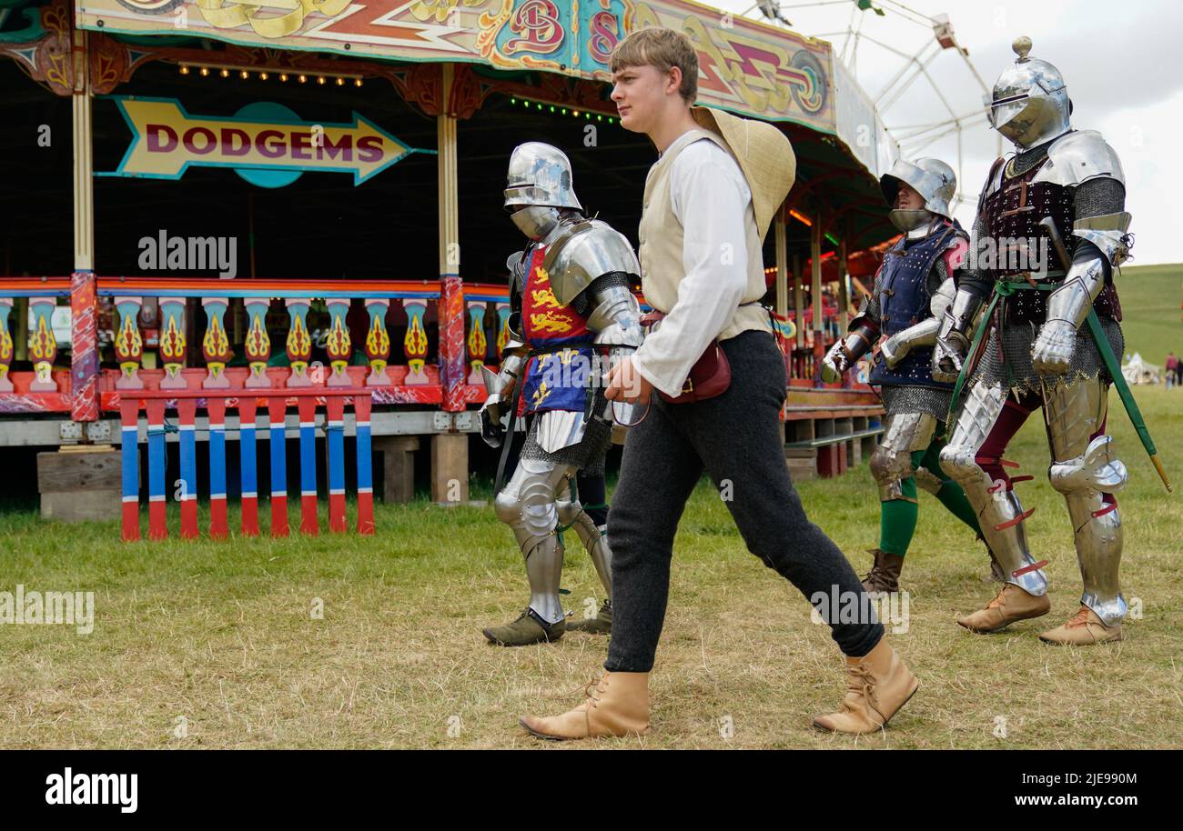 War of the Roses era re-enactors walk past dodgems during the Chalke Valley History festival at Broad Chalke, Near Salisbury, Wiltshire. Picture date: Sunday June 26, 2022. Stock Photo