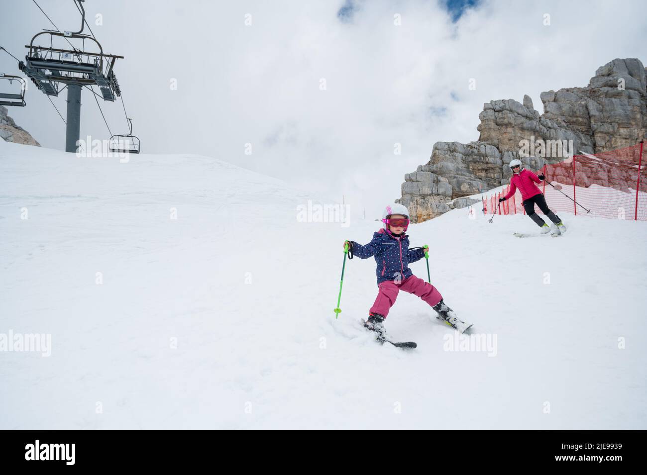 Mother and daughter having fun and learning skiing making first steps