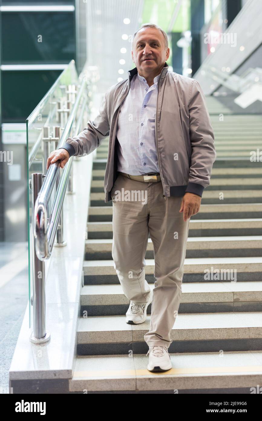 Middle aged man going down stairs in mall Stock Photo