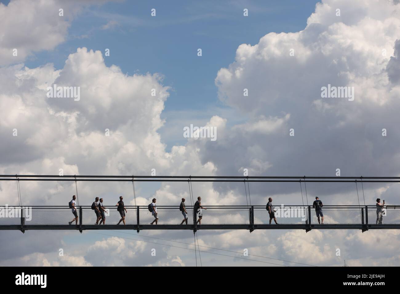 Hasselfelde, Germany. 26th June, 2022. Visitors walk across the suspension bridge at the Rappbode Dam in warm temperatures around 33 degrees. The sunny weather attracted many visitors to the Harz Mountains. Credit: Matthias Bein/dpa/Alamy Live News Stock Photo