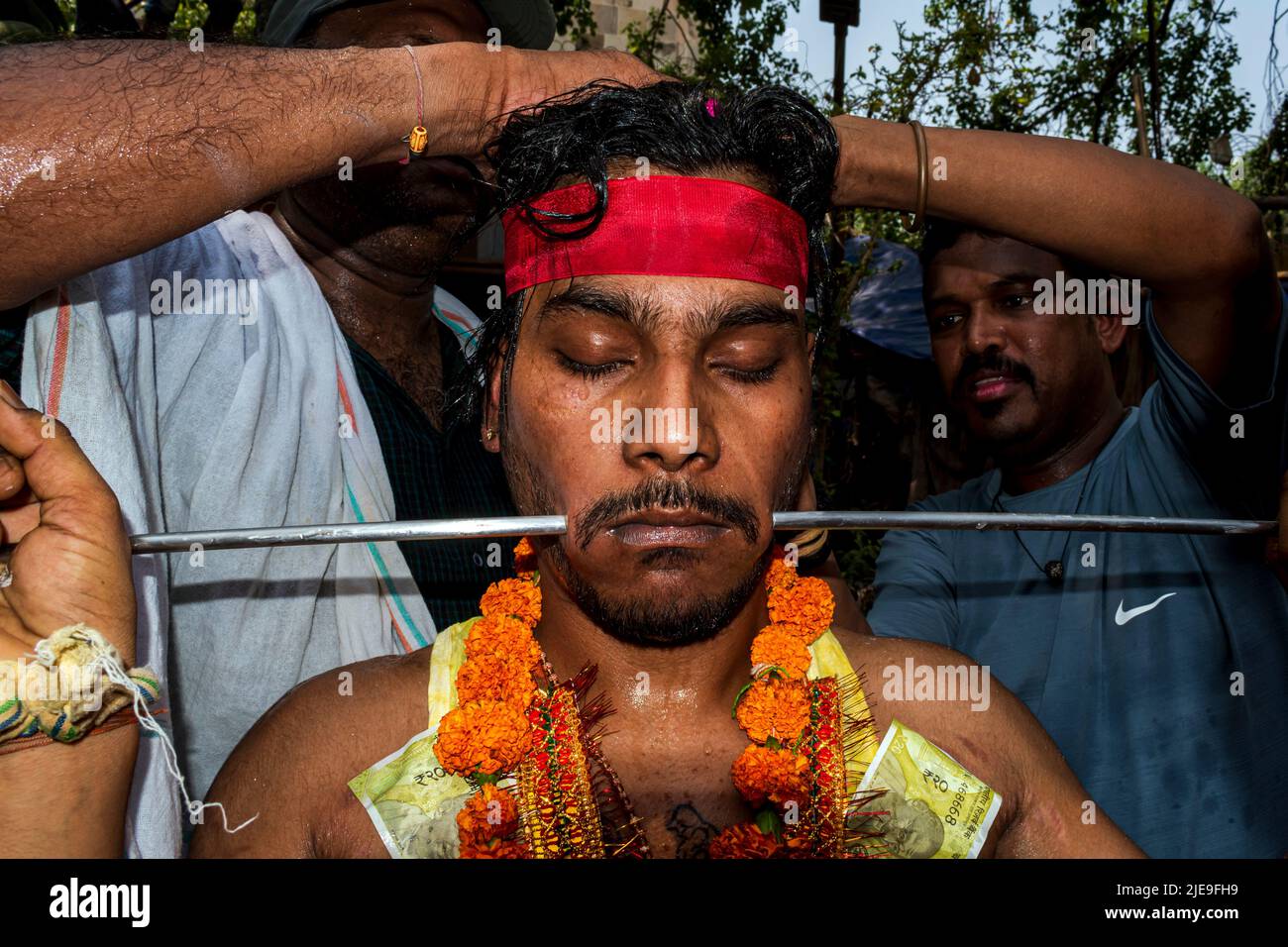 An Indian Hindu devotee has his cheeks pierced with a steel rod by a