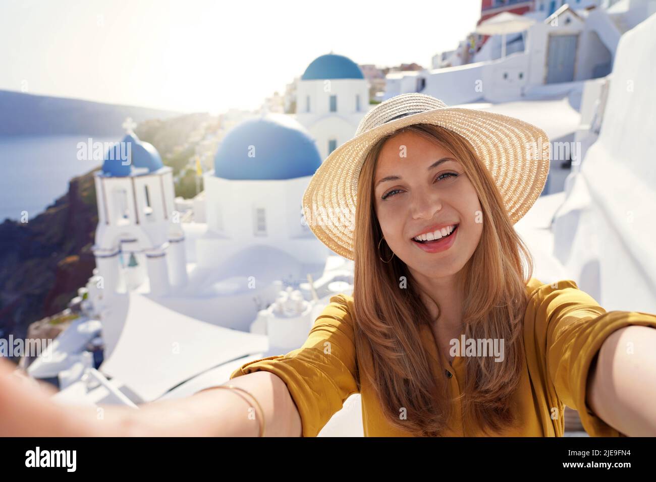 Brazilian young fashion woman taking self portrait on sunset in Santorini Island, Greece Stock Photo