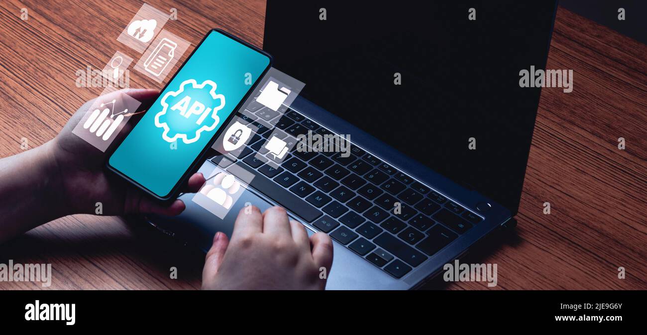 API concept banner with smartphone interface and laptop on desk. Application Programming Interface. Software Development. Stock Photo