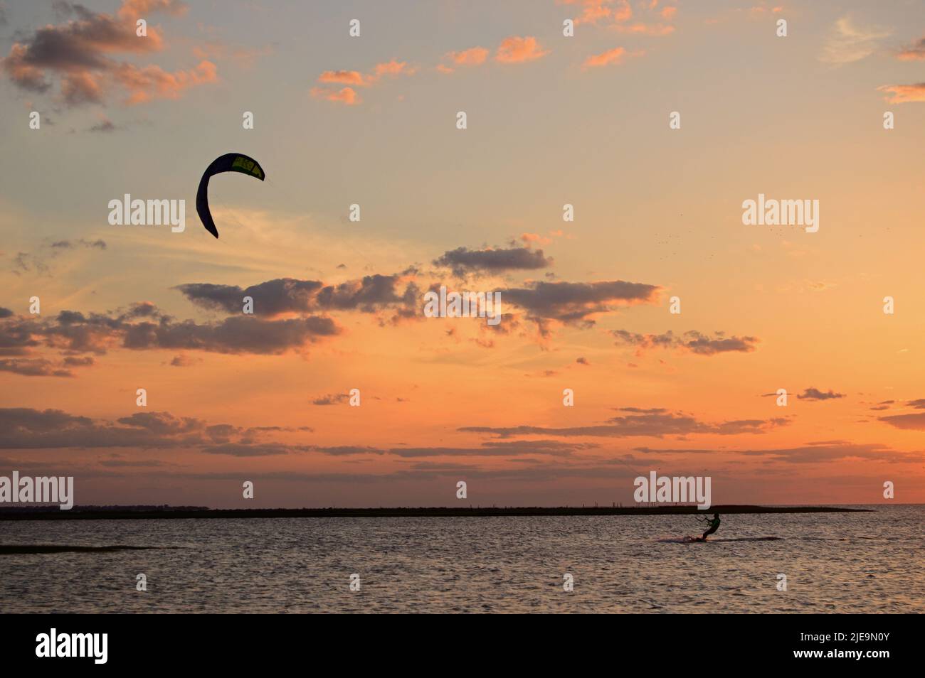 A kite surfer gets in one more ride at sunset Stock Photo