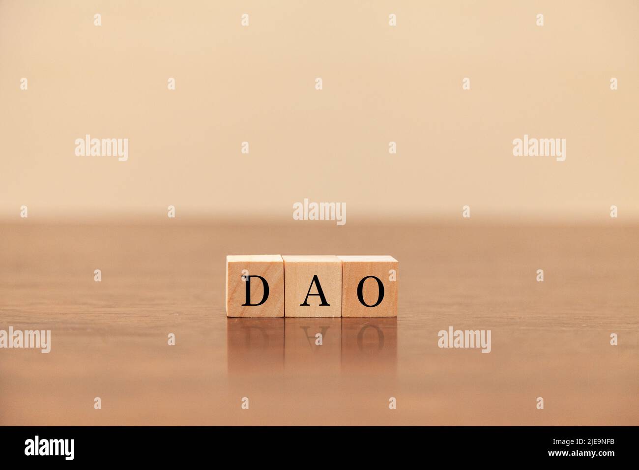 DAO characters. Decentralized autonomous organization. Written on three wooden blocks. Black letters. Wooden table background. Stock Photo