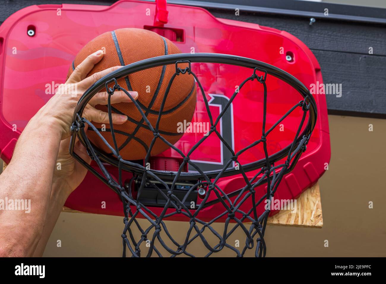 View of man throwing ball into basketball hoop with net while playing basketball. Sweden Stock