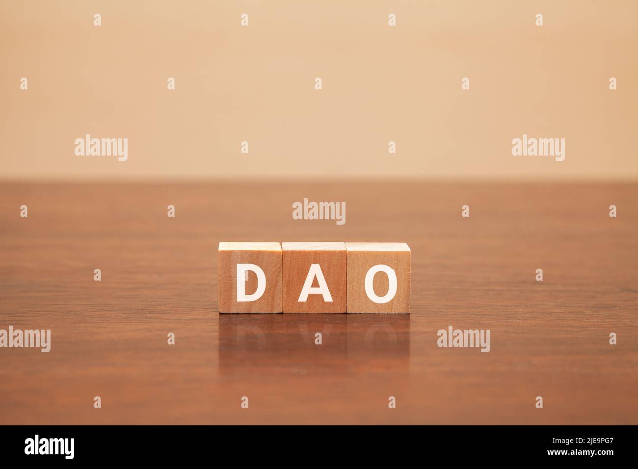 DAO characters. Decentralized autonomous organization. Written on three wooden blocks. White letters. Wooden table background. Stock Photo