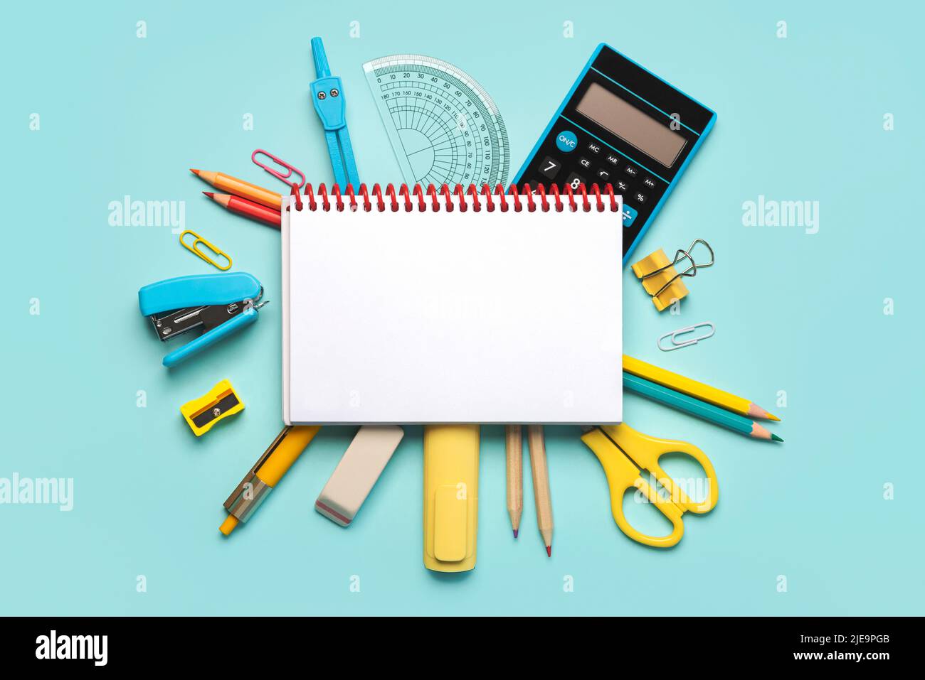 Top view of spiral notepad and school supplies with space for text on blue background. Back to school concept Stock Photo