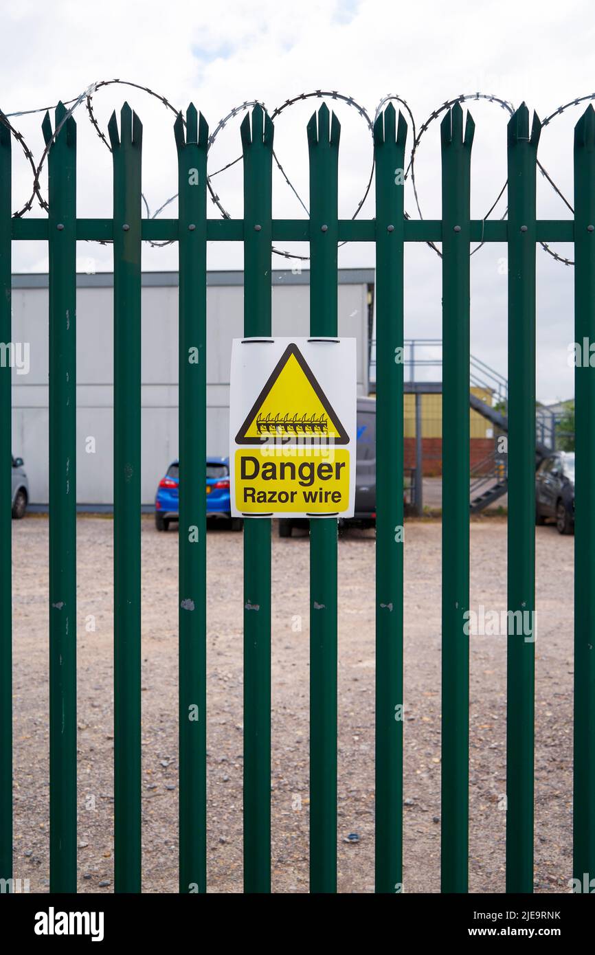 Danger razor wire warning sign on metal security fence Stock Photo