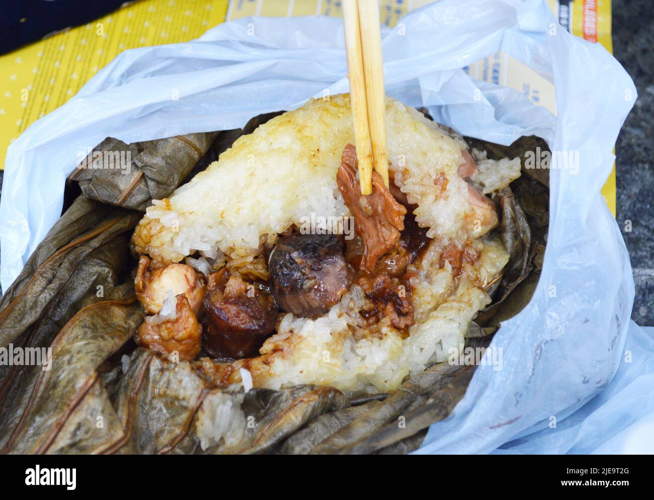 Chopsticks pick up famous Hong Kong dim sum 'Lo Mai Gai', the glutinous rice wrapped by lotus leaf. Stock Photo