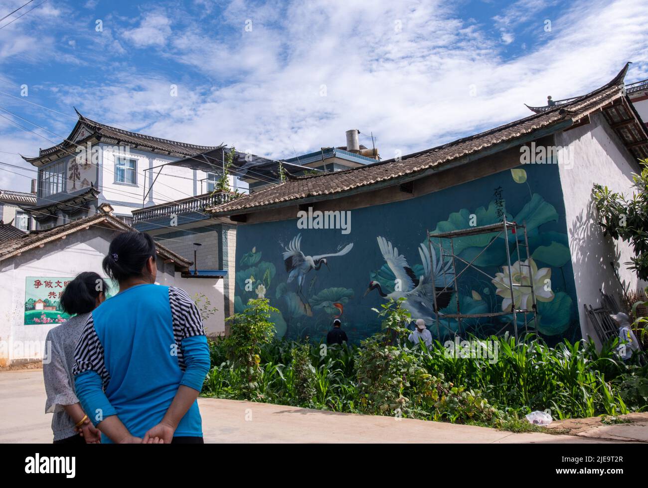 (220626) -- LIJIANG, June 26, 2022 (Xinhua) -- Villagers view Liu Zhicheng's wall painting in Cuihu Village, Sanchuan Township, Yongsheng County, Lijiang City, southwest China's Yunnan Province, June 24, 2022. A non-profit "post-95s" wall painter, hailing from Yongsheng County of Lijiang City, gained popularity both among villagers in his hometown and netizens on social media platforms. The mural artist named Liu Zhicheng has painted more than 20 wall paintings of different themes in many villages of his hometown. His artworks have added color to the villages and attracted many tourists Stock Photo