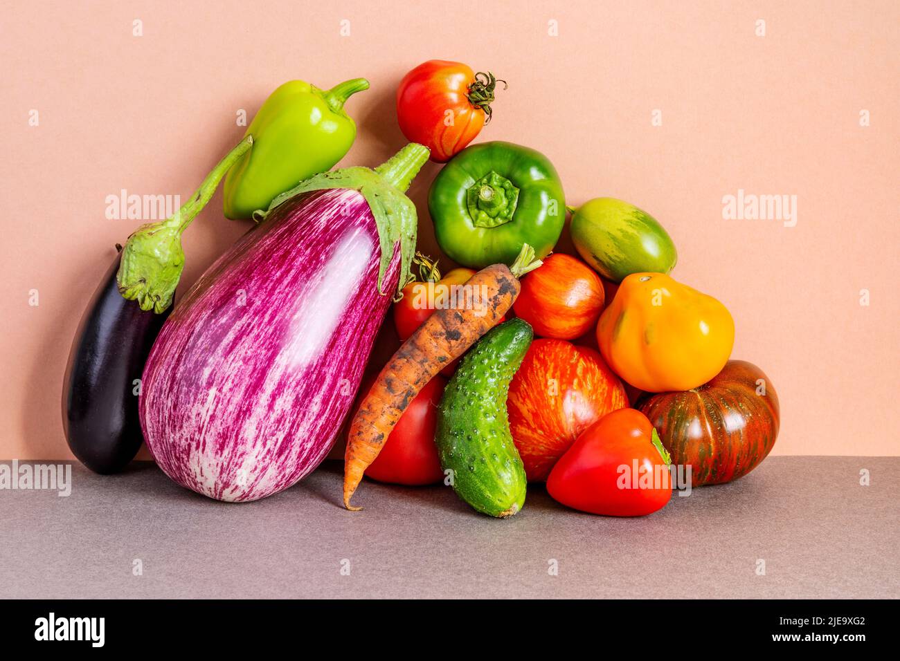 Healthy vegetarian food organic vegetables still life concept. Farm aubergine eggplants, tomatoes of various grade, bell peppers, carrot and cucumber Stock Photo