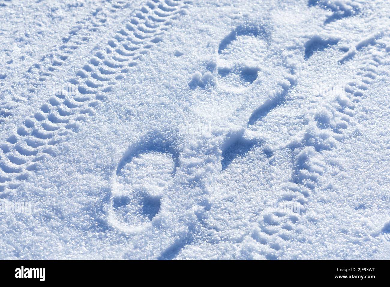 A winter road with shoe footprints, tracks wheel tire tread on white blue fluffy snow background. Fragment of the snowy surface of the earth after the Stock Photo