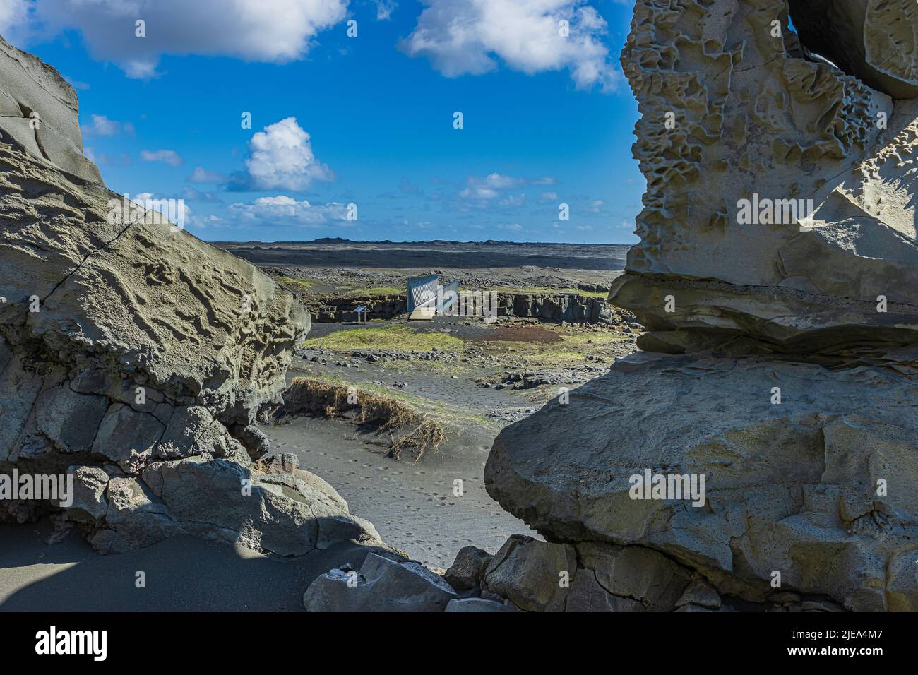 View between two rocks on a bridge. Landscape of Iceland on the Reykjanes peninsula. Lava stones and black lava sand with grass blades. sunshine Stock Photo