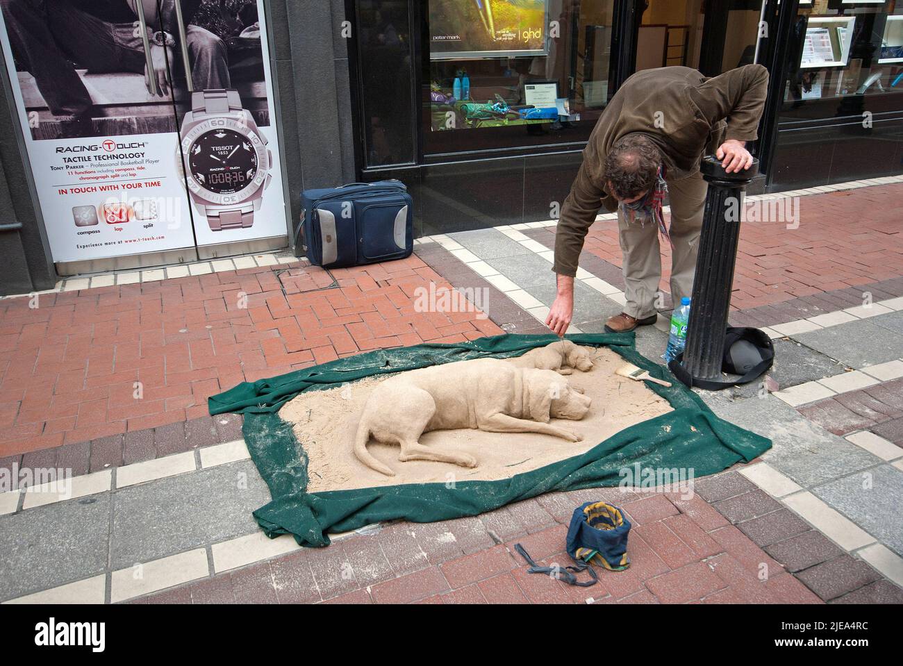 Street artist sculpting a sand dog lying down with her puppy, Grafton Street, Dublin, Ireland Stock Photo
