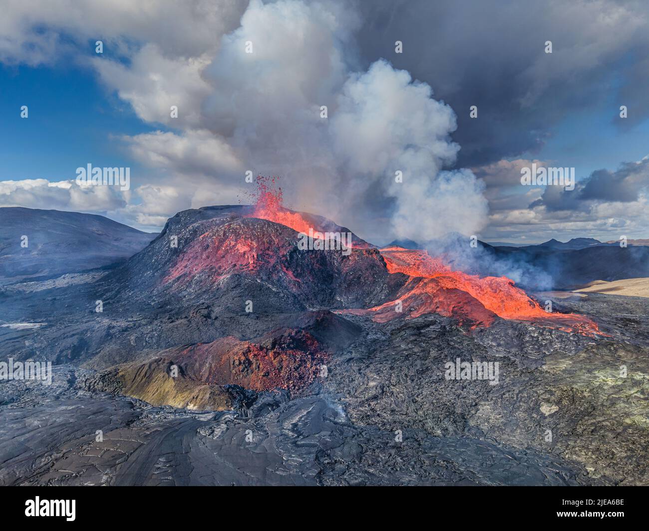 Active volcano with a small fountain from the crater. Volcano with liquid magma on Iceland's Reykjanes Peninsula. green, red gray and dark lava rocks Stock Photo