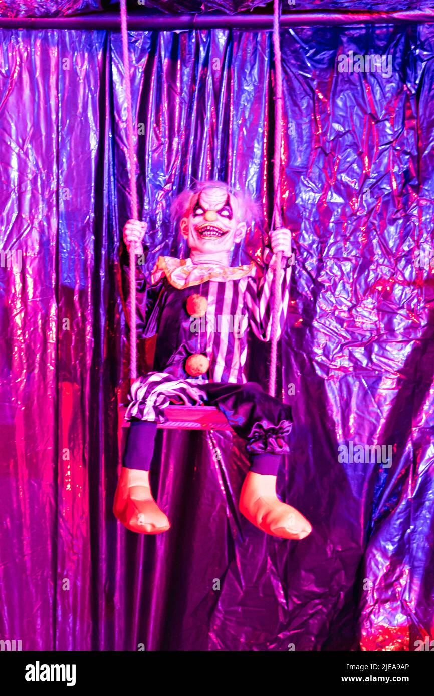 A scary clown decorations in a haunted house for Halloween swinging on