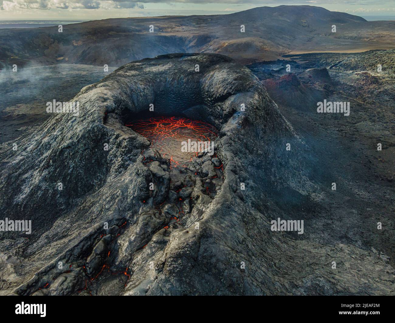 Active volcano in Iceland. View of the volcanic crater. Red lava in the mouth of the volcano on the Reykjanes peninsula during the day. Crater before Stock Photo
