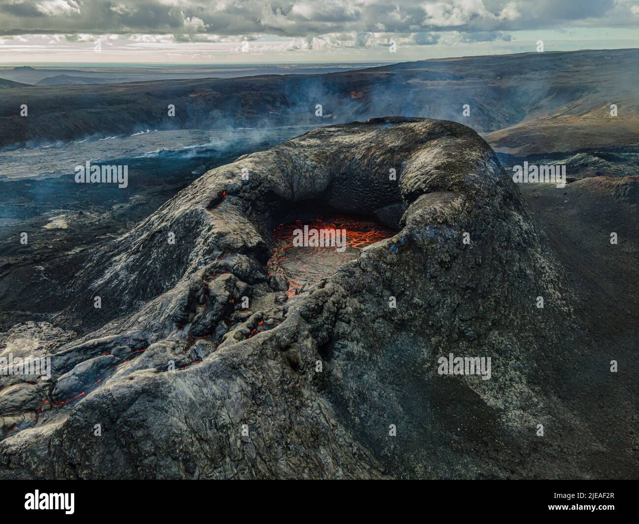 View into the crater with red lava in the mouth. Landscape in Iceland. Volcanic crater on Reykjanes Peninsula by day. Crater before eruption. Dark coo Stock Photo