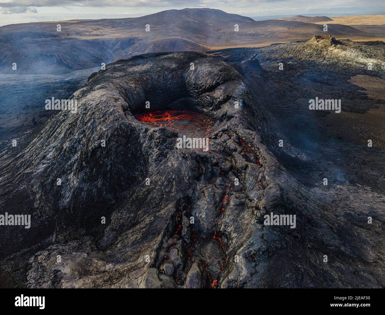 Crater of an active volcano before eruption. Landscape on the Reykjanes Peninsula of Iceland. Liquid lava in the mouth of the volcano crater. Puffs of Stock Photo