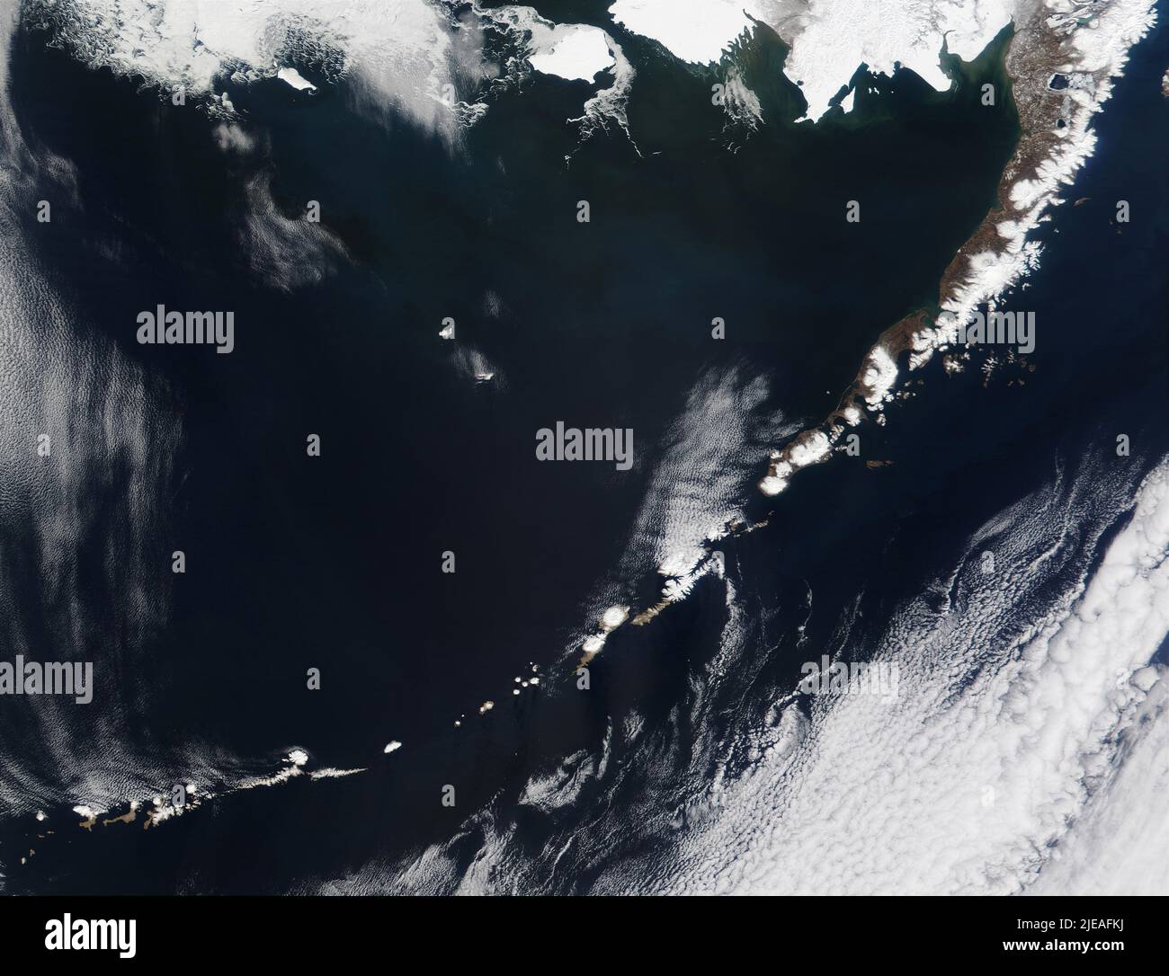 Alaska's Aleutian Islands, northern rim of the Pacific Ring of Fire. The circular white patches of some of the volcanoes' snow-filled craters can be s Stock Photo