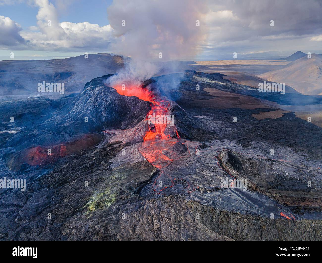 Lava flow with glowing hot magma at volcanic eruption in Iceland. View into the volcanic crater from above during the day. Landscape on the Reykjanes Stock Photo
