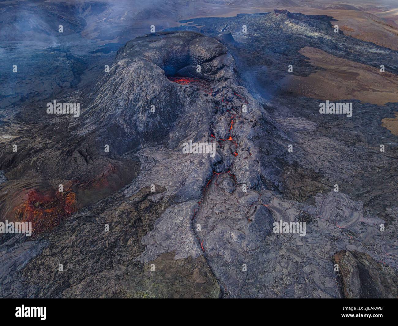 Top view of active volcano on Reykjanes peninsula at day. Volcanic crater in Iceland. Dark magma rock around the crater with little smoke. small lava Stock Photo