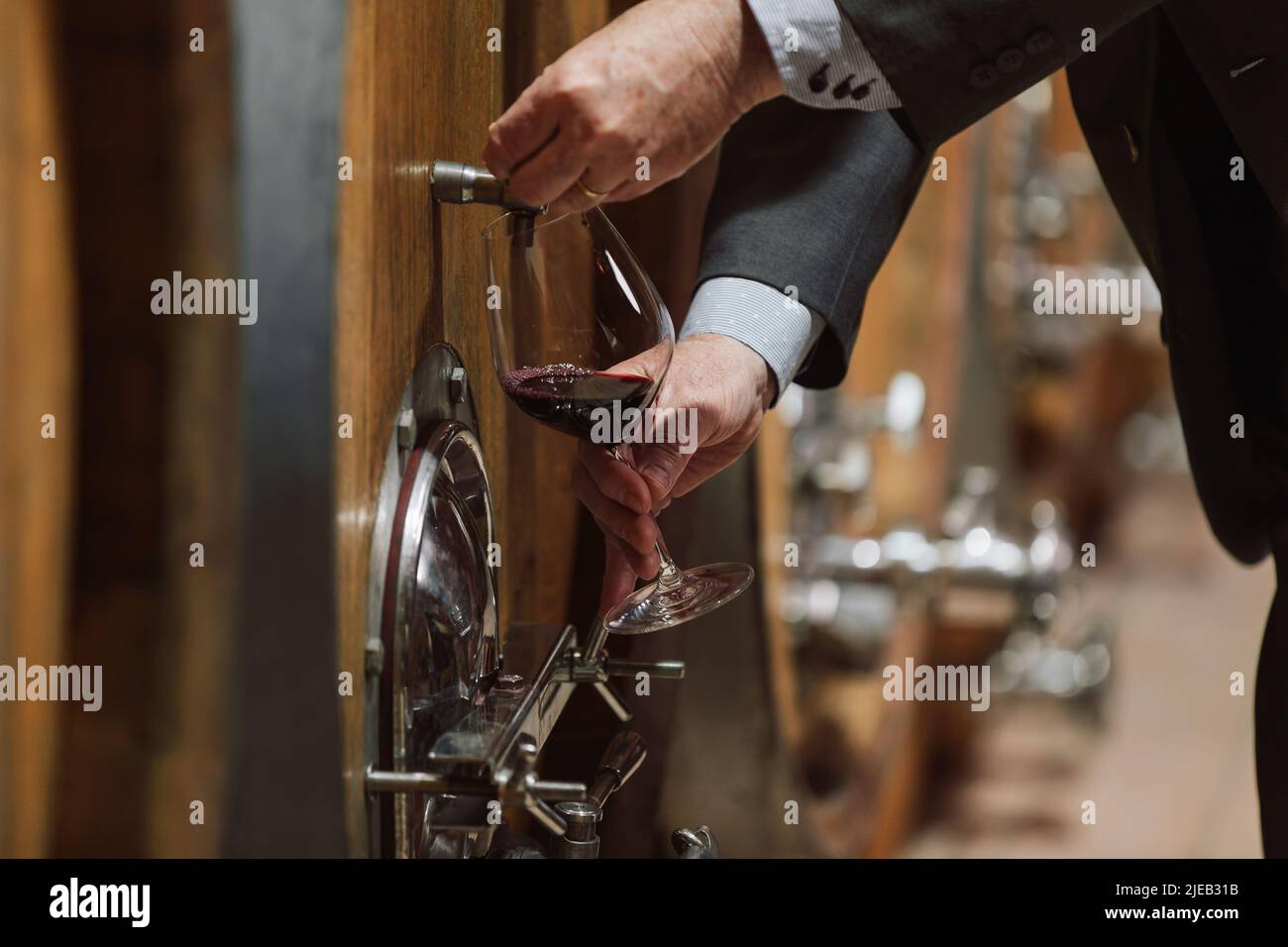 Senior man winemaker at winery checking barrels in wine cellar. Stock Photo