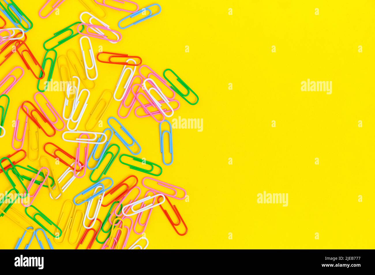 Colored paper clips on a yellow background Stock Photo