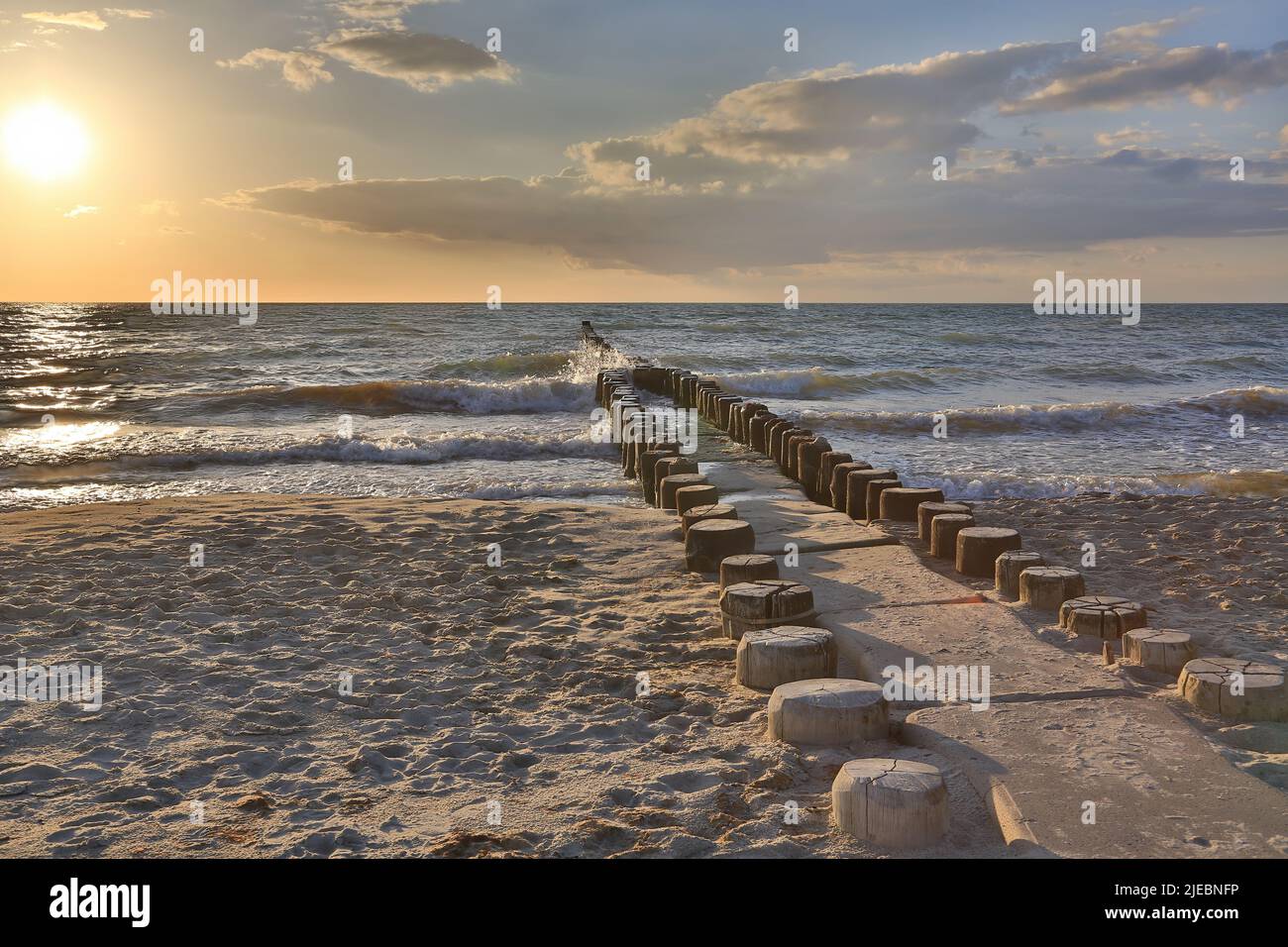 Wooden groynes in the water of the Baltic Sea by the beach at sunset Stock Photo
