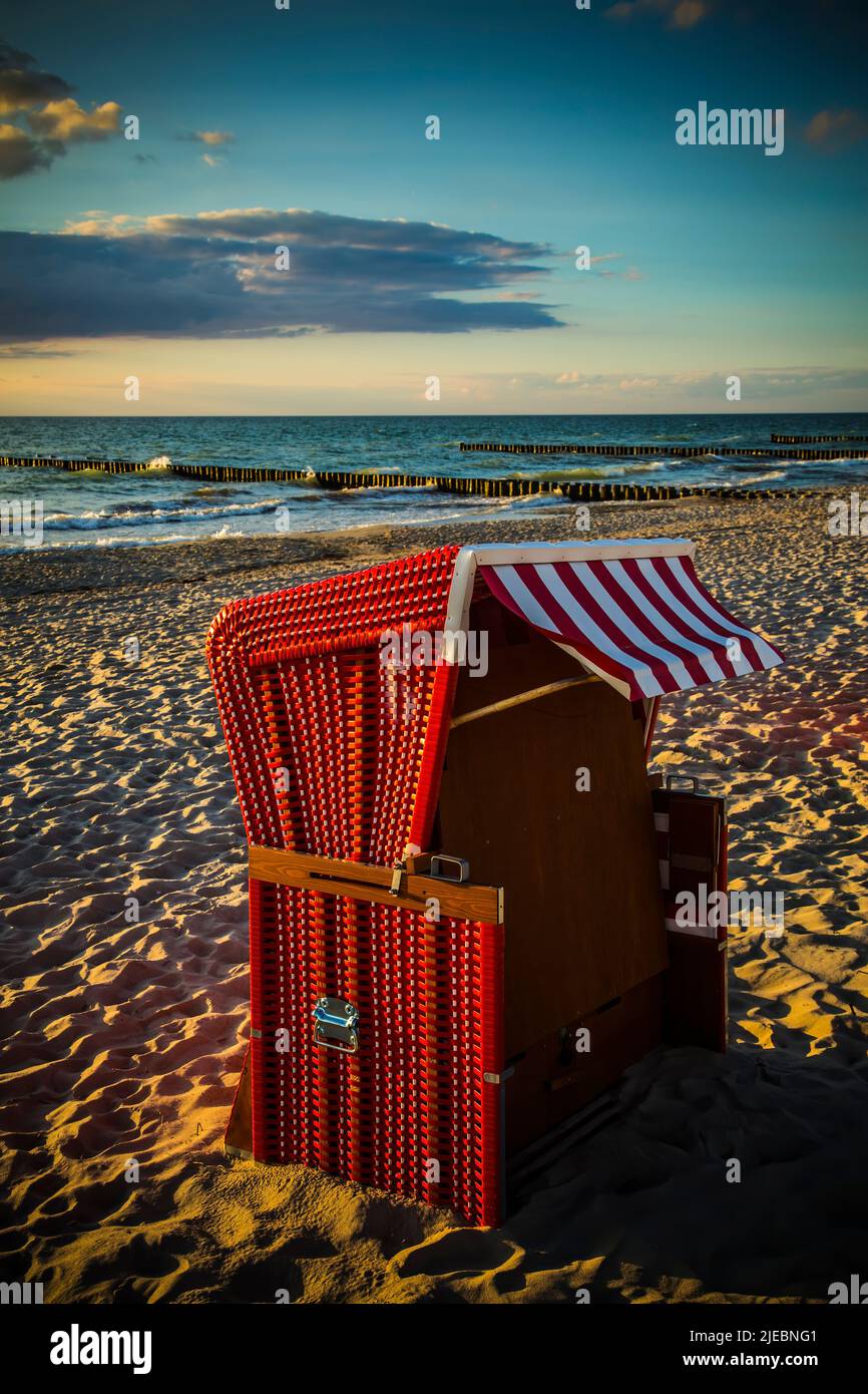 Red traditional beach chair in the sand on the beach of the Baltic Sea at sunset Stock Photo
