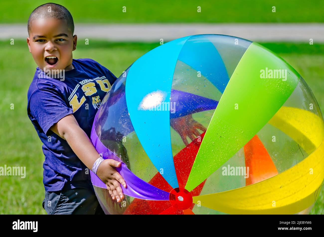 A young African-American boy plays with a giant beach ball, July 27, 2012, in Columbus, Mississippi. Stock Photo