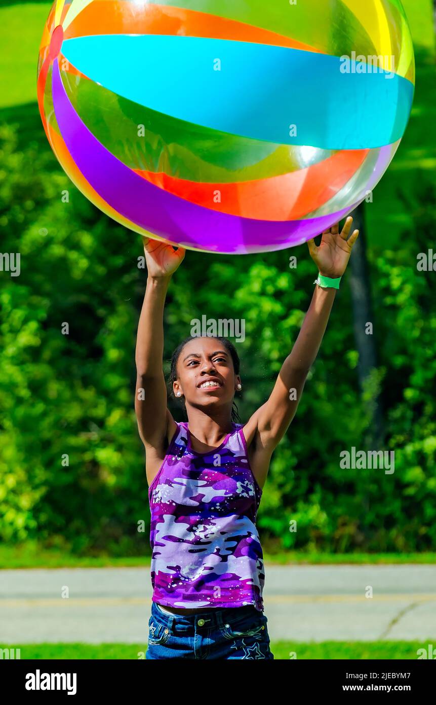 An African-American girl tosses a giant beach ball, July 27, 2012, in Columbus, Mississippi. Stock Photo