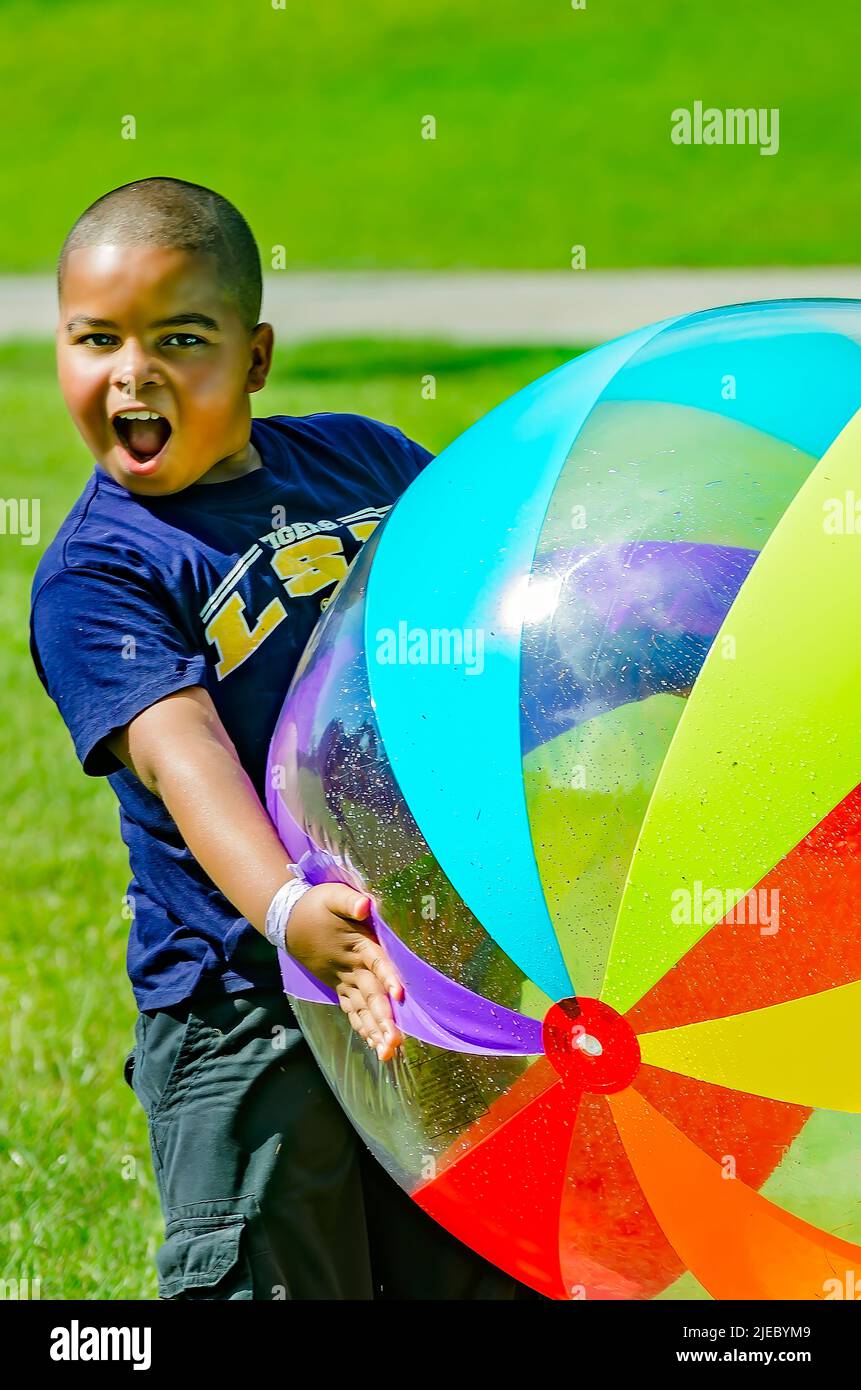 A young African-American boy plays with a giant beach ball, July 27, 2012, in Columbus, Mississippi. Stock Photo
