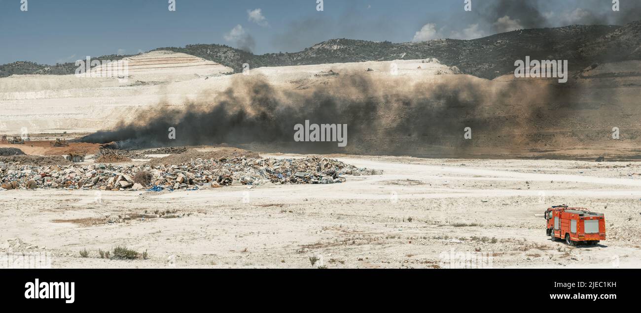 Fire fighting in a tire yard. Panoramic shot of garbage dump with fire truck and earth moving machinery Stock Photo
