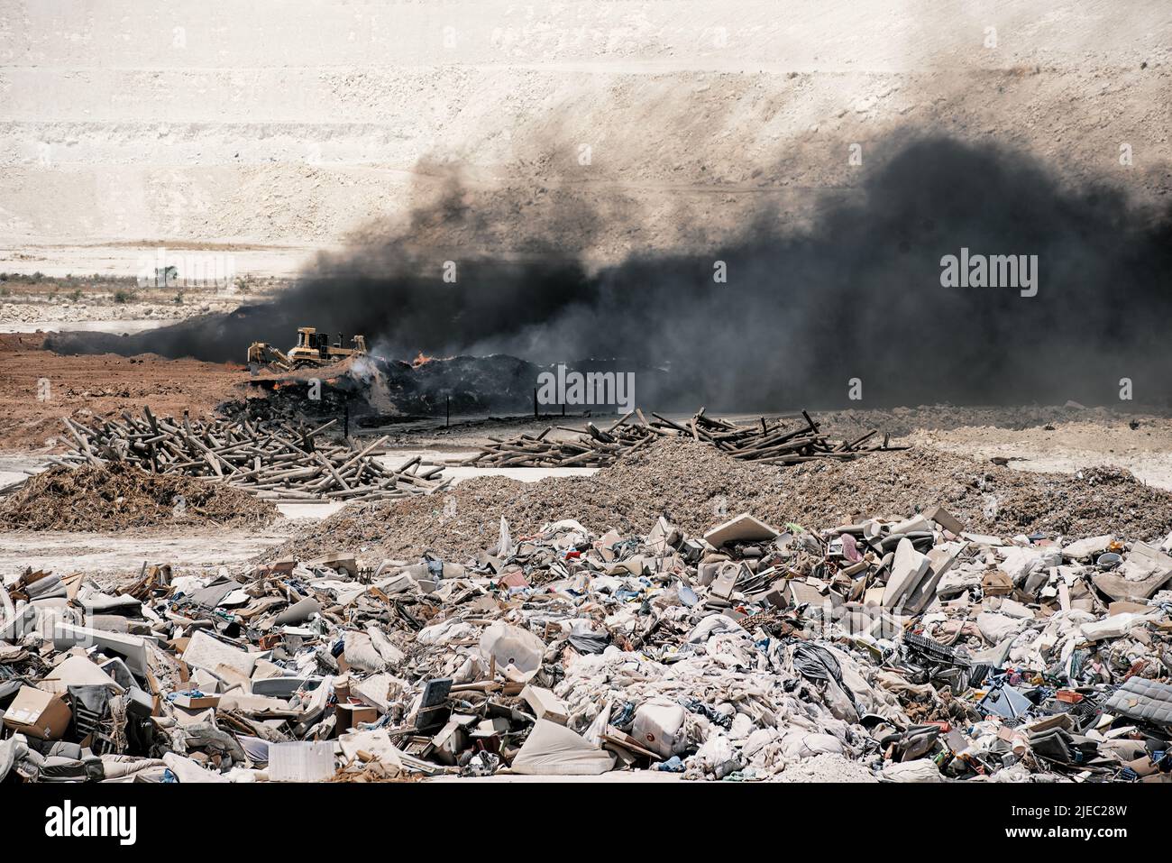 Fire at garbage dump. Black smoke from burning old tyres and bulldozer ...