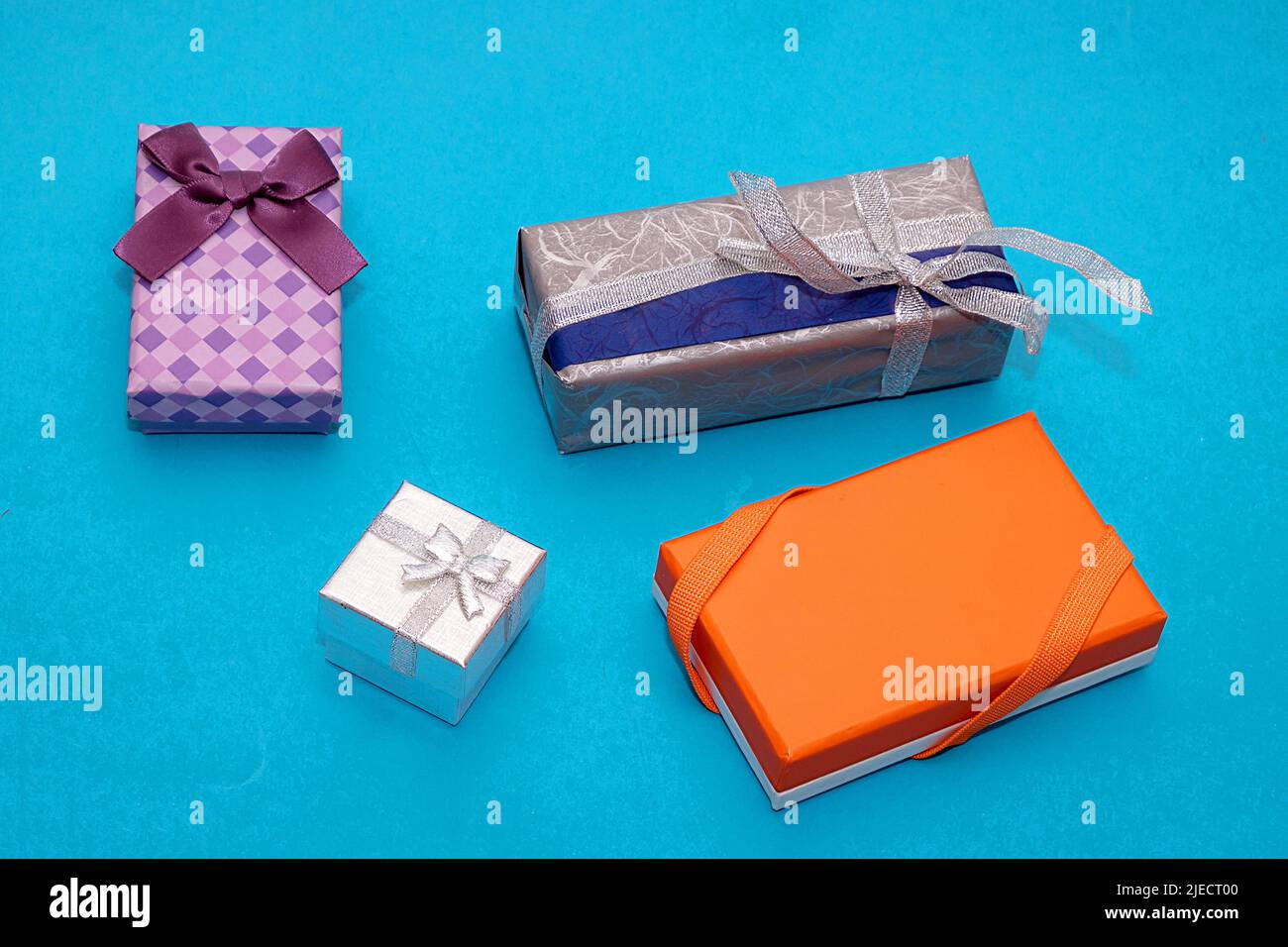 Isolated packed colorful festive gift boxes with bows and silver glitter ribbon on blue background Stock Photo