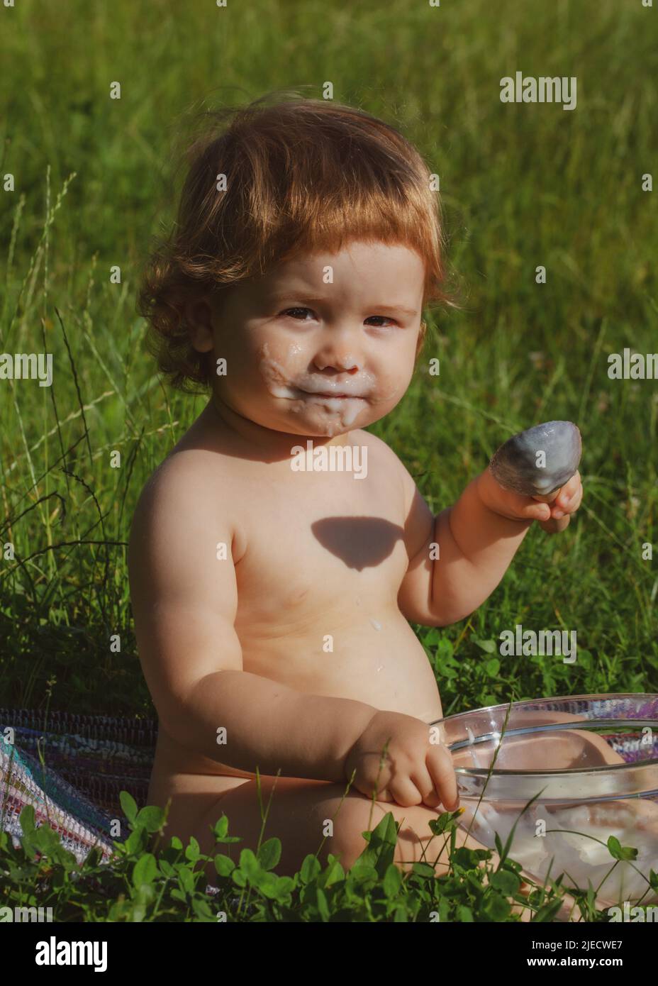 Cute toddler baby eating healthy food. Feeding with spoon. Funny child face. Stock Photo