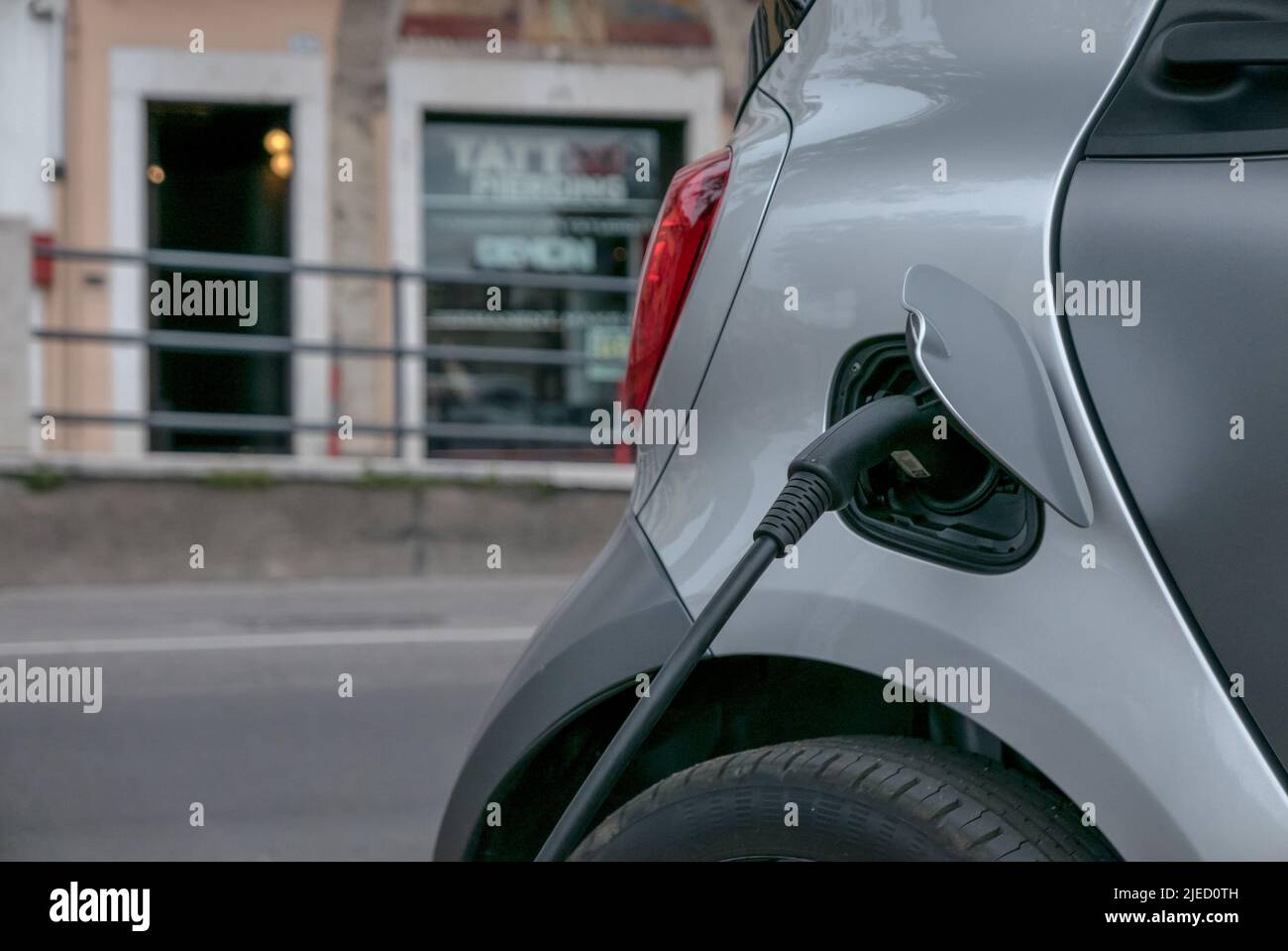 Smart electric car connected to the power plug for charging stock photo