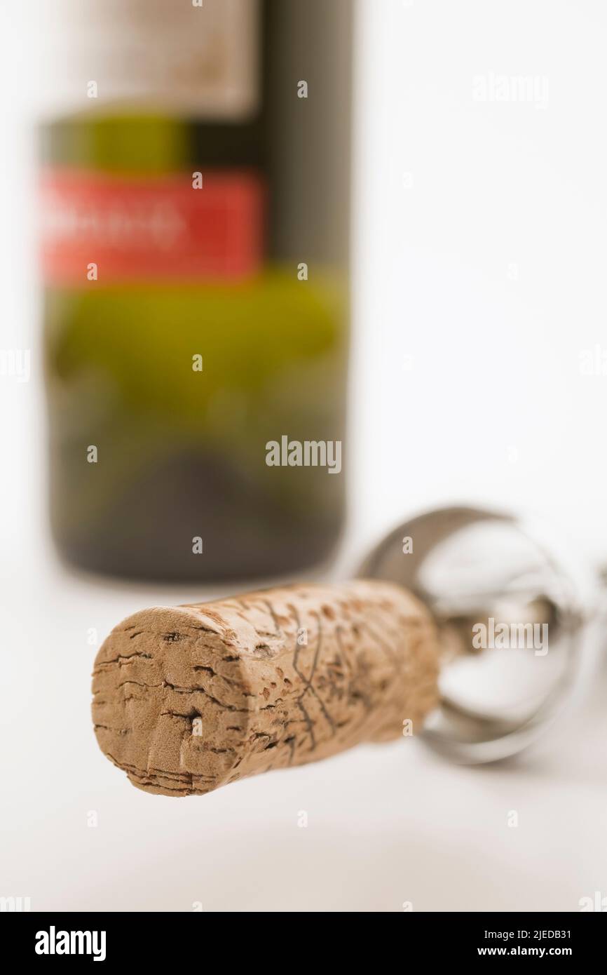 Close-up of cork and corkscrew with wine bottle on white background. Stock Photo