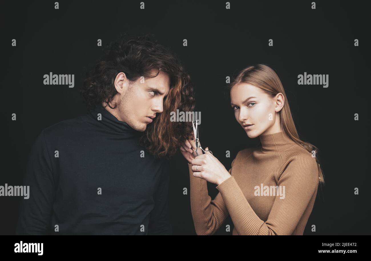 Girl scheming an evil plan of cutting off a curly hair in a man. A smart wily woman has wonderful schemes like a crook of a friend, a dark background Stock Photo