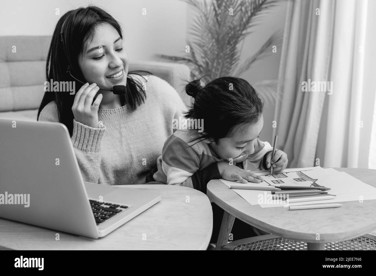 Happy Asian mother working at home with her child son - Family concept - Black and white editing Stock Photo
