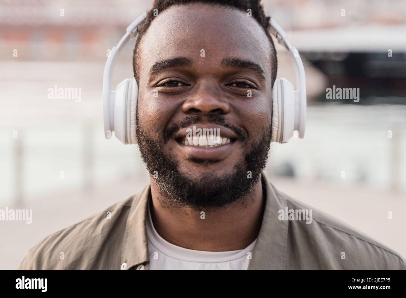 Happy African man with headphones listen playlist music outdoor - Focus on face Stock Photo