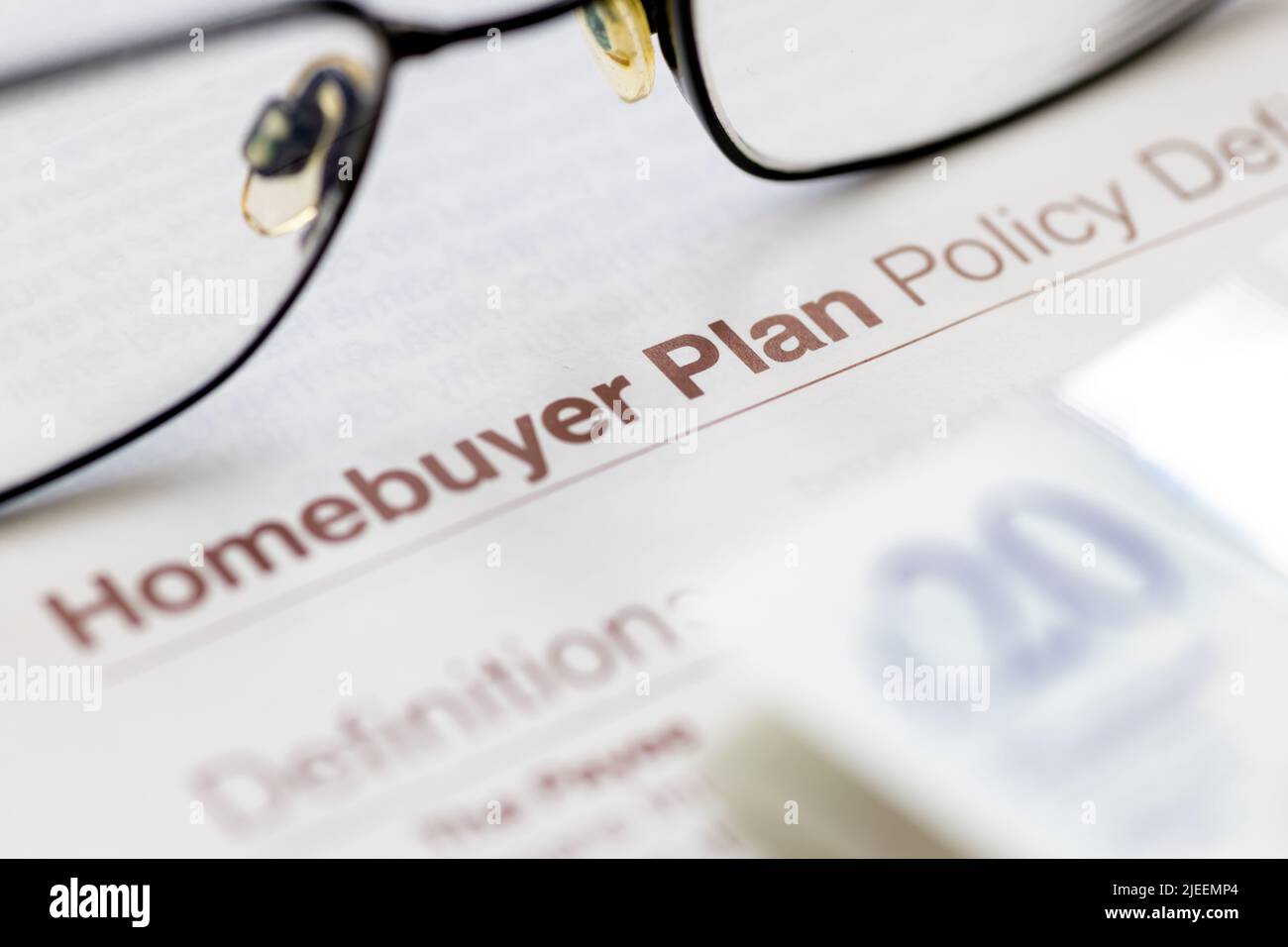 Close up of a life insurance policy document for homebuyer shown with a pair of glasses and bank notes. Stock Photo